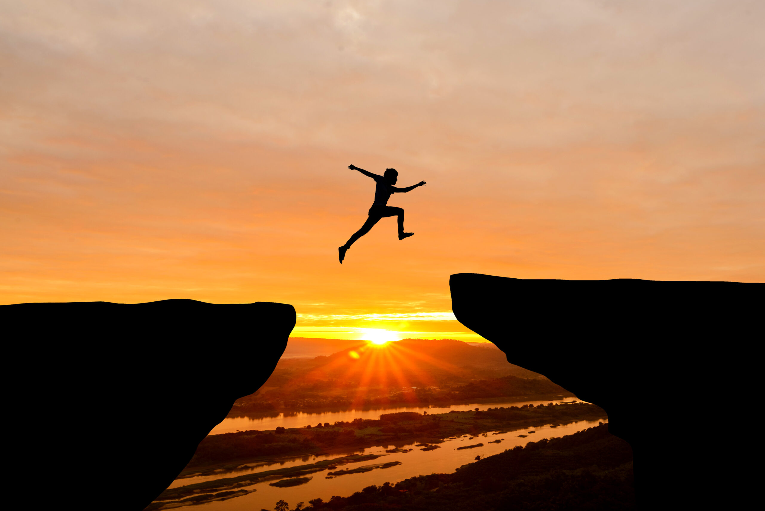 Courage man jumping over cliff on sunset background,Business con